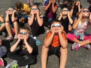 Students wearing protective glasses viewing solar eclipse
