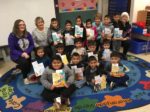 Members of Delta Epsilon pose with kindergartners holding new books